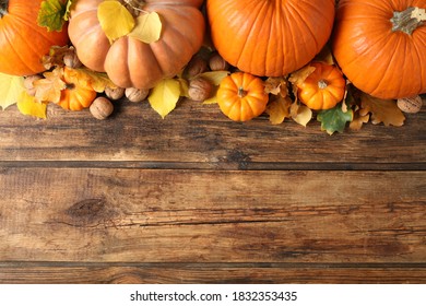 Flat lay composition with ripe pumpkins and autumn leaves on wooden table, space for text. Happy Thanksgiving day