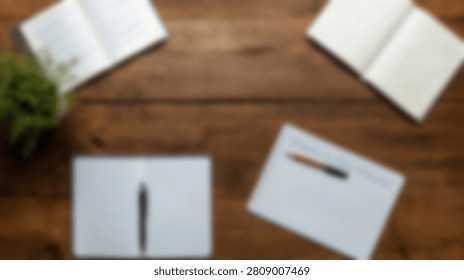 A flat lay composition of a rustic wooden desk featuring two open notebooks, a closed notebook with a pen, and a small potted plant.