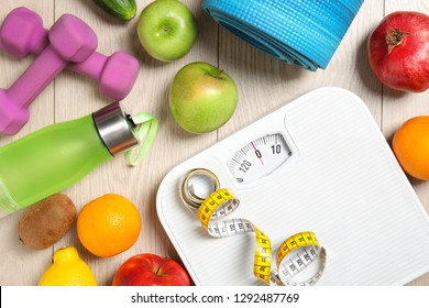 Flat Lay Composition With Scales, Healthy Food And Sport Equipment On Wooden Background. Weight Loss