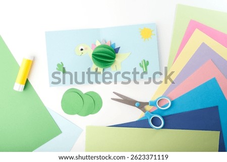 Flat lay composition with scissors, glue stick, colored paper, cut-out shapes. DIY children craft and creative hobby concept for school, kindergarten, education, toy design, art workshop.