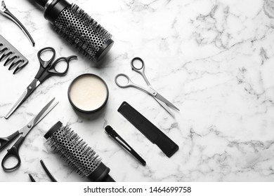 Flat lay composition with scissors and other hairdresser's accessories on white marble background. Space for text