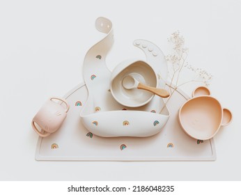 Flat Lay Composition With Set Of Baby Bibs And Plate On Beige Background. Serving Food. Concept Of Kids Menu, Nutrition And Feeding