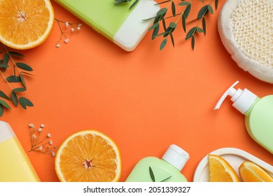 Flat lay composition with shower gel bottles and leaves on orange background, space or text