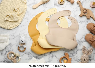 Flat lay composition with silicone baby bibs, toys and accessories on white marble background - Powered by Shutterstock