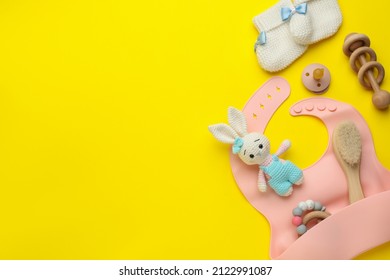 Flat lay composition with silicone baby bib, toys and accessories on yellow background. Space for text - Powered by Shutterstock