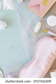 Flat Lay Composition With A Sleep Mask, Perfume, Cosmetic Jars, Massage Roller, Gift Box And Blooming Magnolias On Light Blue Marble Background. Good Morning, Relax And Skin Care Concept. Spring Mood