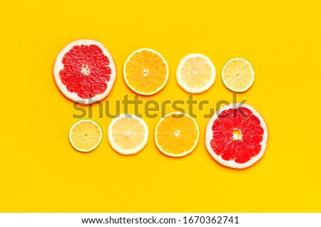 Flat lay composition with slices of fresh lemon orange grapefruit lime on yellow background top view copy space. Citrus Juice Concept, Vitamin C, Fruits. Creative summer background