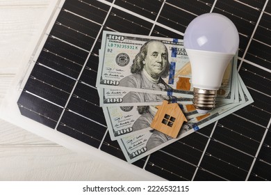 Flat lay composition with solar panel, led lamp, house model and money on  table. Money saving and clean energy concept. Ecology and sustainable development concept.