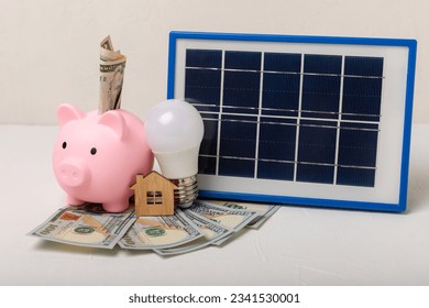 Flat lay composition with solar panel, led lamp, money and piggy bank on texture background. The concept of saving money and clean energy. The concept of ecology and sustainable development.