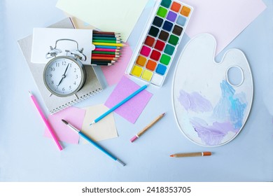 Flat lay composition with stationery, watercolor paints, brushes and colored pencils, palette,on a gray background. Back to school concept. - Powered by Shutterstock