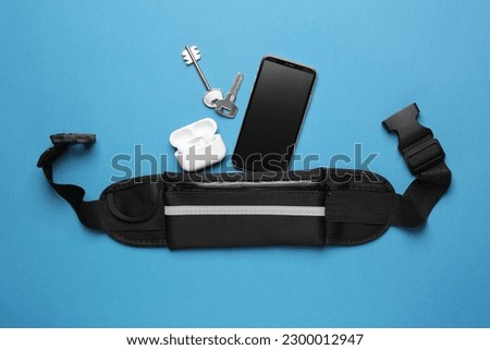 Flat lay composition with stylish black waist bag on light blue background