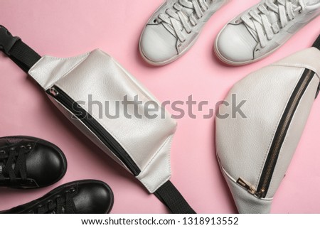 Flat lay composition of stylish shoes and bum bags on color background