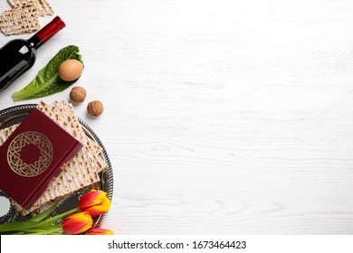 Flat lay composition with symbolic Pesach (Passover Seder) items on white wooden table, space for text