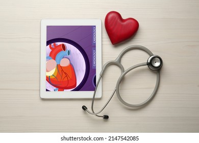 Flat lay composition with tablet and red heart on white wooden table. Cardiology concept