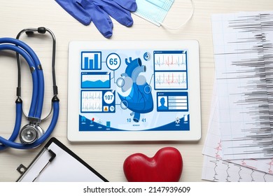 Flat lay composition with tablet and red heart on white wooden table. Cardiology concept