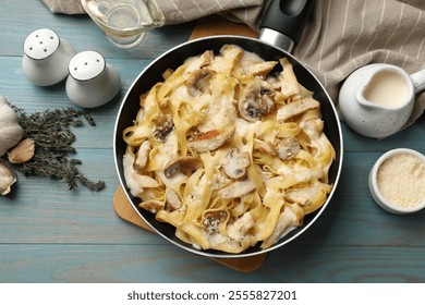 Flat lay composition with tasty Alfredo pasta with chicken and mushrooms on light blue wooden table - Powered by Shutterstock