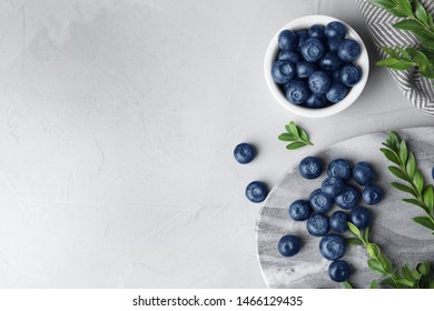 Flat lay composition with tasty blueberries on grey table, space for text