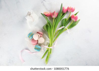 Flat lay composition with tasty macarons, tulips and gift box on light background