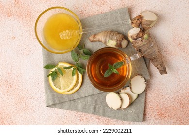 Flat lay composition of tea with mint, honey, lemon and ginger on beige textured table - Powered by Shutterstock