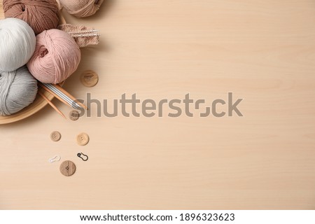 Flat lay composition with threads and crafting accessories on wooden table, space for text. Engaging hobby