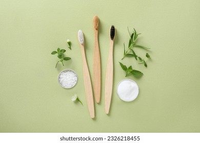 Flat lay composition with toothbrushes and herbs on light olive background