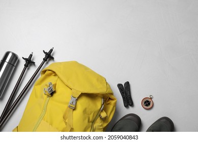 Flat lay composition with trekking poles and other hiking equipment on light background, space for text