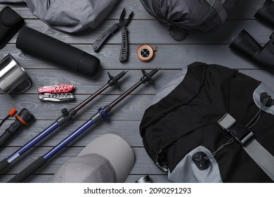 Flat lay composition with trekking poles and other hiking equipment on grey wooden background