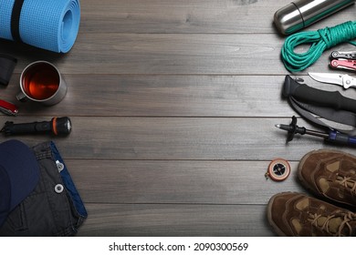 Flat lay composition with trekking poles and other hiking equipment on wooden background, space for text