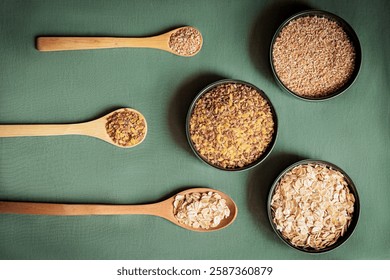 Flat lay composition of various grains and cereals in wooden spoons and bowls on a green background. Healthy eating, organic food, and nutrition concept. Minimalist food styling