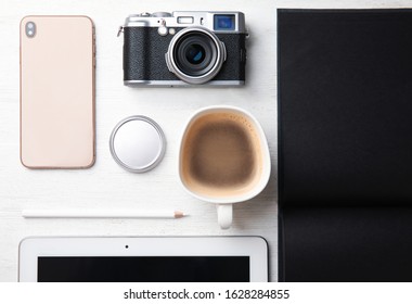 Flat lay composition with vintage camera and smartphone on white wooden table. Designer's workplace