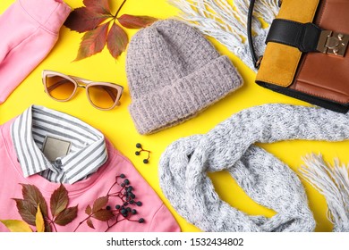 Flat lay composition with warm clothes and autumn leaves on yellow background