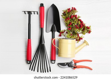 Flat lay composition with watering can and gardening tools on white wooden table