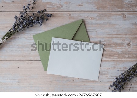 Flat lay composition of white paper greeting card on envelope with dry lavender flowers. Copy space template mock up. Top view. Concept of Wedding invitation postcard. Business advertisement
