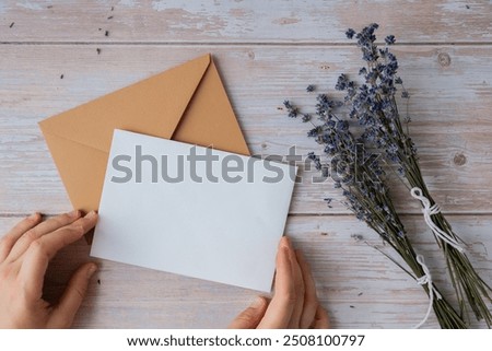 Flat lay composition of white paper greeting card on envelope with dry lavender flowers. Copy space template mock up. Top view. Concept of Wedding invitation postcard. Business advertisement