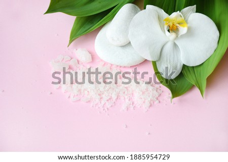 Flat lay composition with white spa sea salt and white orchid with space for text on pink background. Meditation and minimalism. copyspase flatlay. Spa cosmetic and Beauty concept, top view. 