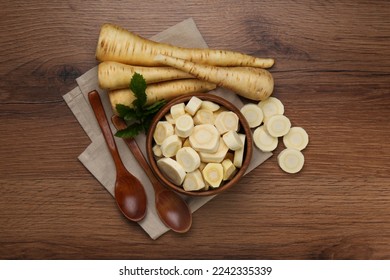Flat lay composition with whole and cut fresh ripe parsnips on wooden table - Shutterstock ID 2242335339