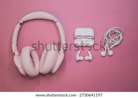 Flat lay composition of wireless over ear headphones, wireless earbuds and wired earphones on a pink background. Audio technology concept with copy space for advertising or branding.