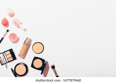 Flat lay composition of women's makeup products and accessories in corner on white background with copy space.
