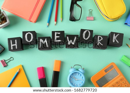 Flat lay composition with word HOMEWORK made of black cubes on green background
