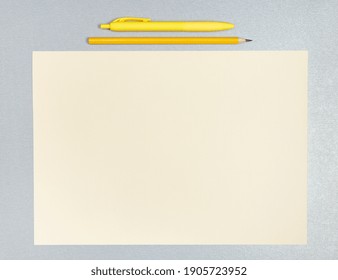 Flat lay composition of yellow pen, pencil and sheet of yellow paper on a gray surface