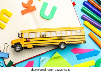 Flat lay composition with yellow school bus model on light blue background. Transport for students