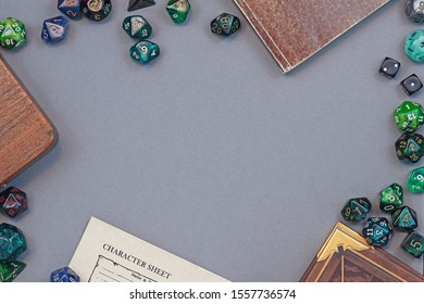 Flat Lay Concept Design For Tabletop Role Playing With Colorful Green And Blue Dices, Character Sheet And Rule Books With Empty Copy Space On Gray Background