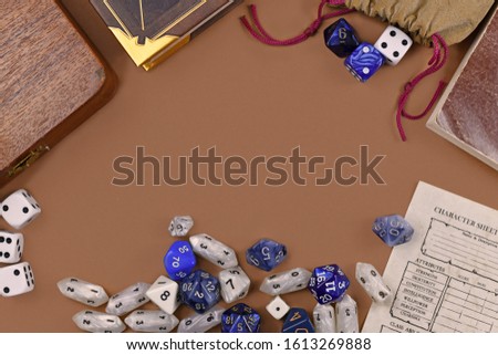 Flat lay concept design for tabletop role playing with colorful blue and white RPG dices, character sheet and rule books with empty copy space on brown background