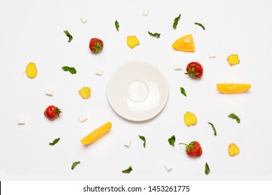 Flat lay concept empty white plate, sugar cubes, strawberries, ginger slices, orange and mint leaves. Objects are arranged in the form of a circle.