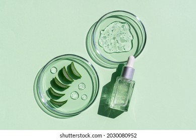 Flat lay of cosmetics serum and and laboratory glassware with fresh leaves of aloe vera on bright green background. Organic cosmetics. Top view flat lay, copy space. Cosmetics, SPA branding, mock-up. - Shutterstock ID 2030080952