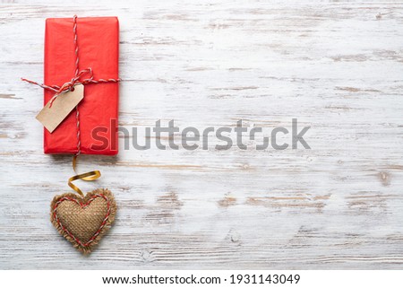 Flat lay cute composition with handmade fabric red hearts. Red gift box on wooden table. Happy birthday or anniversary congratulation. Romantic love story template with copy space.