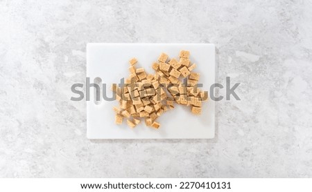 Flat lay. Cutting stale bread with a bread knife on a white cutting board to make croutons.
