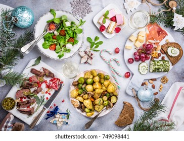 Flat Lay Of Delicious Christmas Themed Dinner Table With Roasted Meat Steak, Appetizers And Desserts. Top View. Holiday Concept.