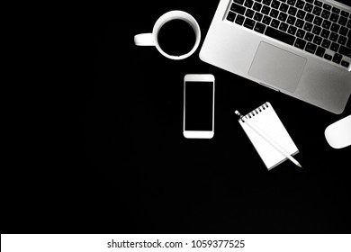 Flat lay design of work desk with laptop notebook coffee and smartphone on black background. Top view of modern working space.