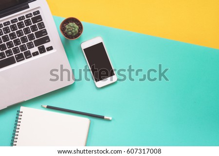 Flat lay design of work desk with labtop notebook, smartphone and cactus on green and yellow background. 